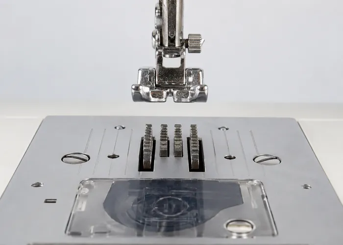 Dentes de transporte visíveis acima da chapa de uma máquina de costura