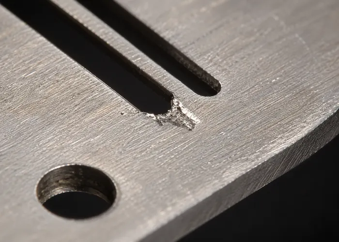 Marca recente de impacto de agulha na borda do furo da chapa